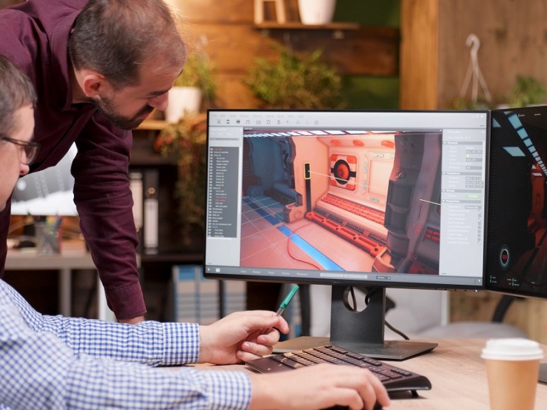 Graphic designer in gaming industry talking detail with his colleague analyzing 3d design level